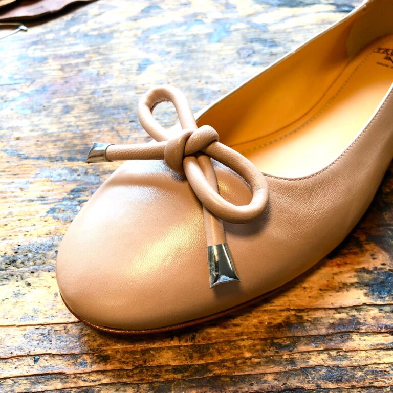 Schuhspitze eines rosa Ballerina Schuh mit einer Schleife aus Leder drauf