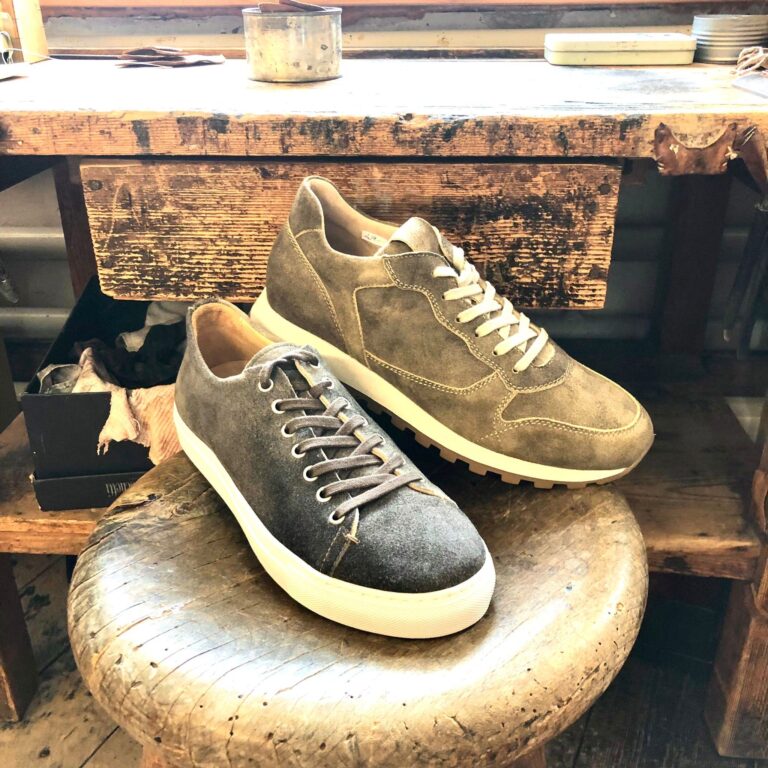 Ein hellbrauner und ein dunkelbrauner Trachtensneaker mit einer weissen Sohle