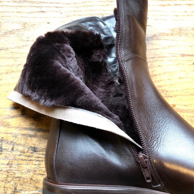 Das dunkelbrauner Lammfellfutter eines braunen Winterboots aus Leder nach außen geklappt